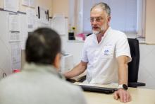 Un metge conversa amb el pacient en una consulta. Estan asseguts en una taula.