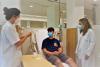 Pacient jove estirat en un llit a l'hospital de dia de l'Hospital Santa Caterina amb dos professionals sanitaris que li fan una prova d'al·lèrgia